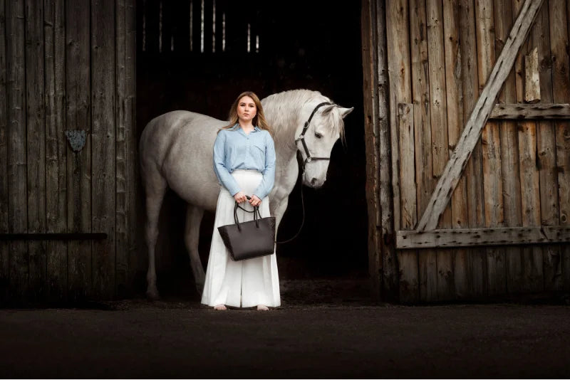 Alpha Pajé: blonde model presents quiet luxury handbags. She is accompanied by a white horse in the background.