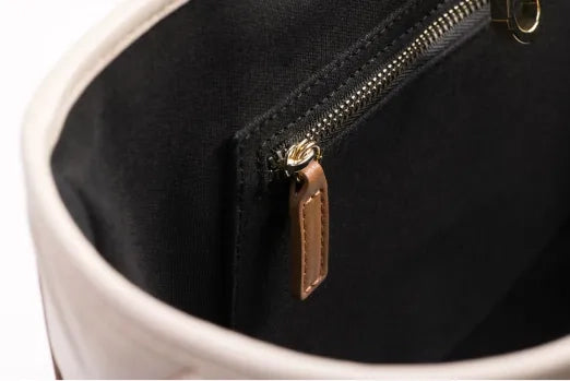 Product photo: close-up of a zipper with a brown leather pull.